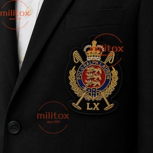 May include: A black blazer featuring a white collared shirt underneath and a prominent embroidered crest on the chest. The crest displays a crown, three lions, crossed polo mallets, and the text Polo Ralph Lauren with the Roman numeral LX.