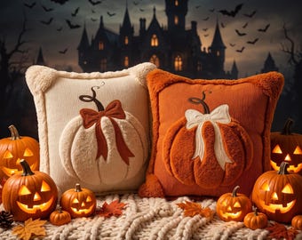 Puede incluir: Dos cojines cuadrados, uno crema y otro naranja, con aplicaciones de calabaza de felpa y lazos. El cojín crema tiene un lazo color óxido, mientras que el naranja tiene un lazo crema. Ambos cojines presentan bordes de tela texturizada.