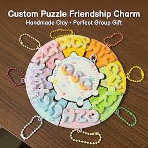 May include: A colorful, handmade clay puzzle friendship charm. The puzzle is round with multiple pieces, each with a letter or number. The center piece has the letters "QVA". Each piece has a small chain attached. The text "Custom Puzzle Friendship Charm" is at the top.