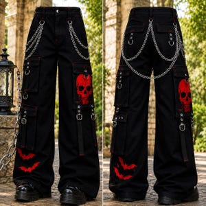 May include: Black cargo trousers featuring a red skull graphic on the side pocket and red bat silhouettes near the hem. The trousers include silver-toned metal chains attached to the waist and pockets, along with multiple utility straps and metal D-rings.