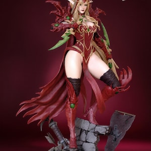 May include: A detailed figurine of a female fantasy character in a dynamic pose. The figure wears a red and gold outfit with green accents, a flowing cape, and high boots. The base includes a stone structure and a banner.