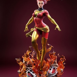 Peut inclure: Figurine détaillée d'une super-héroïne dans une pose dynamique, debout sur une base enflammée. La figurine porte un costume rouge et or avec un col noir et un emblème d'étoile dorée. Les cheveux sont coiffés en rouge flamboyant, et la base présente des flammes et des débris.