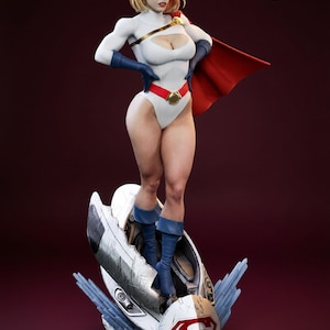 May include: A detailed statue of a female superhero in a white bodysuit with a red cape. She has blonde hair, blue gloves, and boots. The statue is standing on a futuristic base with a Superman logo.