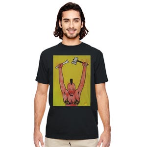 Puede incluir: Camiseta negra con un diseño gráfico colorido. El diseño muestra a una persona con cresta y top de bikini, sosteniendo un hueso y un hacha sobre la cabeza, sobre un fondo amarillo.