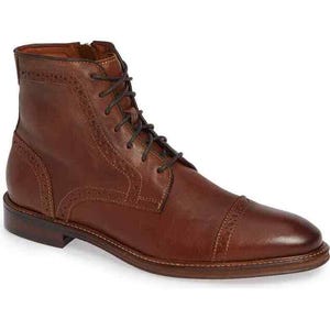 May include: A brown leather ankle boot featuring a cap toe design with decorative brogue detailing along the seams. The boot includes dark brown laces, a side zipper closure, and a stacked heel with a smooth, polished finish on the leather upper.
