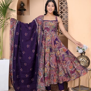 May include: A purple Indian suit. The sleeveless top and trousers are complemented by a patterned shawl. The top has a paisley design in purple, orange, and pink. This outfit is suitable for special occasions and cultural events.