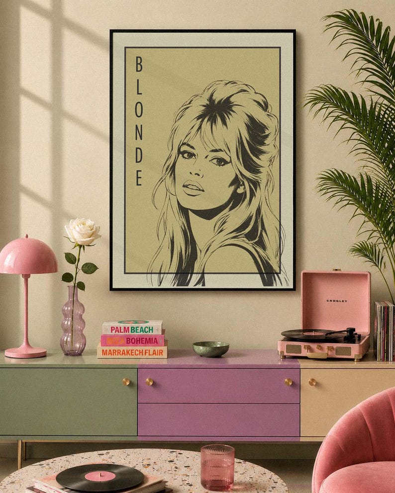 May include: A framed art print featuring a black and white illustration of a woman with the word "BLONDE" vertically printed on the left. The print hangs above a colorful cabinet with books, a record player, and a pink lamp.