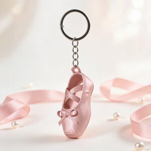 Puede incluir: Un llavero de zapatilla de ballet rosa claro que presenta una zapatilla de punta en miniatura con cintas cruzadas y un peque&ntilde;o lazo en la punta. El zapato est&aacute; unido a una anilla de metal plateado mediante una cadena corta.