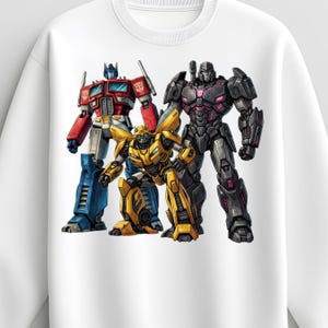 Peut inclure: Sweat-shirt blanc avec une illustration de trois personnages de Transformers : Optimus Prime en rouge et bleu, Bumblebee en jaune et Megatron en noir et violet. Illustration détaillée.