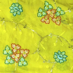 May include: A vibrant lime green fabric featuring embroidered floral motifs in shades of light blue, pink, and red. The design includes delicate swirling vine patterns accented with shimmering silver sequins that trace the stems and petals.