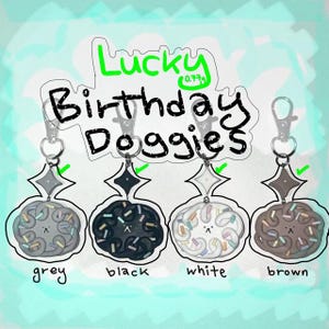 Peut inclure: Quatre porte-clés avec un motif sur le thème des chiens. Chaque porte-clés présente une couleur différente : gris, noir, blanc et marron. Le texte "Lucky Birthday Doggies" est écrit au-dessus des porte-clés.