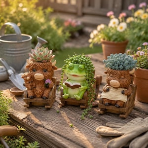 Könnte beinhalten: Drei dekorative Pflanzgefäße aus Kunstharz in Form von Tieren, die in Schaukelstühlen sitzen. Ein braunes Hochlandrind hält ein Kalb, ein grüner Frosch liest ein Buch und ein weiteres braunes Hochlandrind hält ein Papier. Jeder Topf enthält eine Sukkulente.