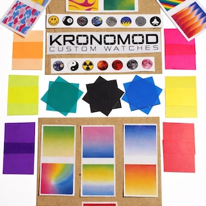 Puede incluir: Una colección de pegatinas y calcomanías coloridas, con diseños degradados, llamas y patrones geométricos. Las pegatinas están dispuestas sobre una superficie de cartón, con el texto "KRONOMOD CUSTOM WATCHES".