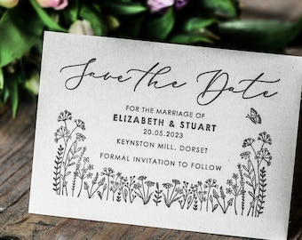 以下が含まれることがあります： 「Save the Date」のカードで、花柄の縁取りと「Save the Date」の文字が筆記体で書かれています。カードには、「For the marriage of Elizabeth & Stuart 20.05.2023 Keynston Mill, Dorset Formal invitation to follow.」という文章も書かれています。