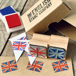 以下が含まれることがあります： 赤、白、青のユニオンジャックの旗が描かれた木製スタンプ4個セット。スタンプは、"The English Stamp Company"と書かれた茶色の箱に入っています。