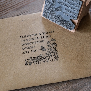 以下が含まれることがあります： 花柄のデザインと「ELIZABETH & STUART 74 ROWAN ROAD DORCHESTER DORSET DT1 1BY」という文字が印刷された黒と白のゴム印です。