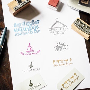May include: A collection of rubber stamps with various designs, including a tent, a pie, mushrooms, a hanger, a garlic, and a phrase that says "naturlige NOWEGIAN DESIGN".