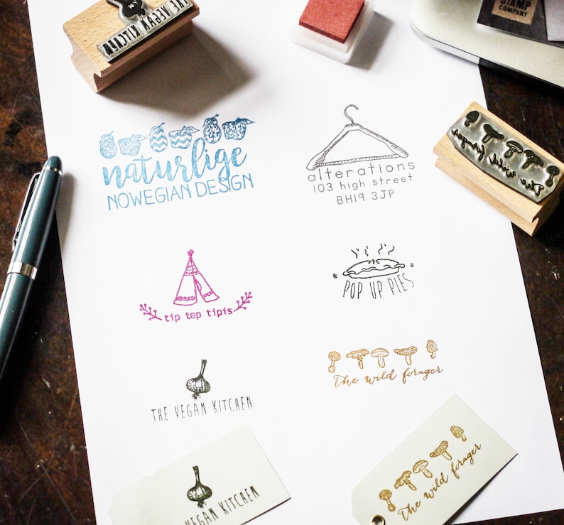 May include: A collection of rubber stamps with various designs, including a tent, a pie, mushrooms, a hanger, a garlic, and a phrase that says "naturlige NOWEGIAN DESIGN".