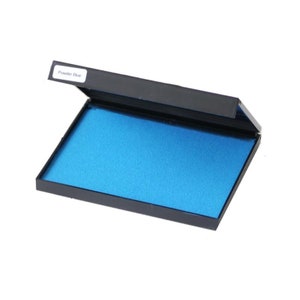 May include: A blue ink pad in a black plastic case with the label "Powder Blue" on the lid.