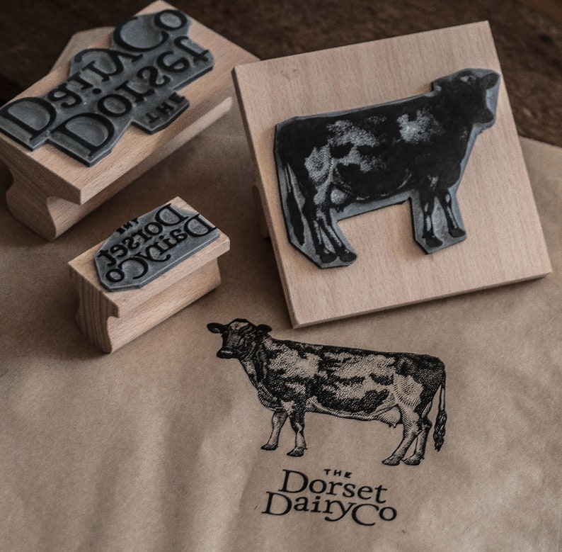 May include: Three wooden blocks with black ink stamps of a cow and the text "The Dorset Dairy Co."