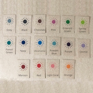 May include: A chart of 18 colour swatches, each with a sun graphic and a colour name. The colours include grey, black, chocolate, pink, emerald green, spring green, forest green, navy, ultramarine, powder blue, purple, orchid, maroon, red, light coral, and orange.