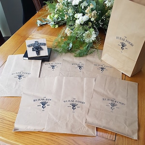 K&ouml;nnte beinhalten: Sieben braune Papiert&uuml;ten mit dem Logo "The Rural Food Co. Est. 2017" bedruckt. Das Logo zeigt eine Schwarzwei&szlig;illustration einer R&uuml;be.