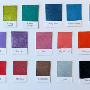 K&ouml;nnte beinhalten: Farbkarte mit 18 Farbmustern, jedes mit einem Namensschild. Die Farben umfassen Smaragdgr&uuml;n, Fr&uuml;hlingsgr&uuml;n, Waldgr&uuml;n, Marineblau, Ultramarin, Puderblau, Orchidee, Lila, Rosa, Koralle, Orange, Rot, Weinrot, Schokolade, Grau und Schwarz.
