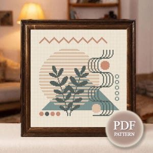 May include: A framed cross-stitch pattern featuring an abstract design with a beige background. The design includes a zig-zag line, a circle with horizontal lines, and a plant with leaves. The color palette includes shades of beige, teal, and coral. A PDF pattern is available.