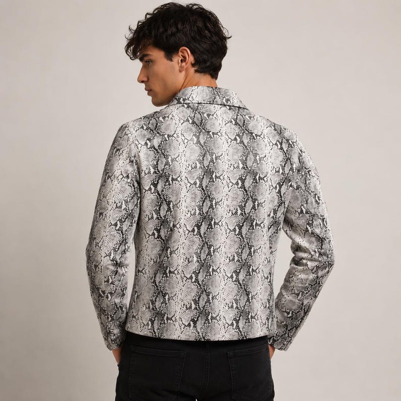 Peut inclure: Une veste &agrave; manches longues arborant un motif peau de serpent monochrome dans des tons de gris, noir et blanc. La veste pr&eacute;sente un col structur&eacute;, une fermeture boutonn&eacute;e sur le devant et une coupe ajust&eacute;e, port&eacute;e sur un pantalon noir.