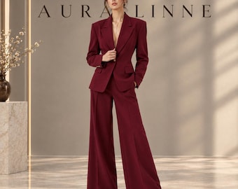 Op de afbeelding: Een diepbordeauxrood broekpak bestaande uit een getailleerde blazer met inkepingen in de revers en een enkele knoopsluiting, gecombineerd met een bijpassende broek met hoge taille en wijde pijpen. De tekst AURA LINNE staat in zwart boven het pak.