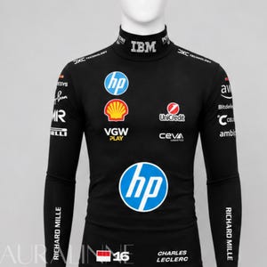 Op de afbeelding: Een zwart shirt met lange mouwen en een opstaande kraag, voorzien van diverse sponsorlogo's waaronder HP, Shell, UniCredit, VGW Play, Ceva, IBM en Richard Mille. Het shirt toont de naam Charles Leclerc, het nummer 16 en een Indonesische vlag.