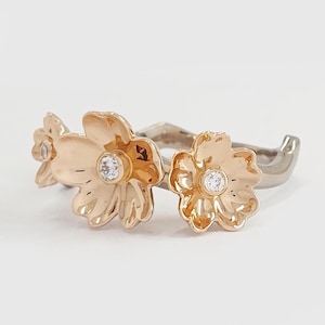 May include: A gold ring with three flower-shaped accents, each with a small clear stone in the center.