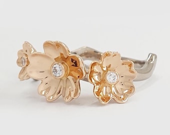 May include: A gold ring with three flower-shaped accents, each with a small clear stone in the center.