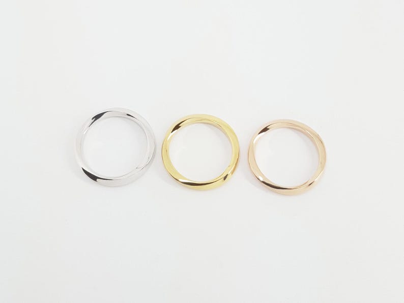 May include: Three simple, twisted metal bands in silver, gold, and rose gold.