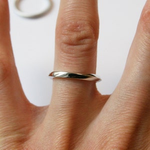 May include: A simple silver band ring worn on a finger.