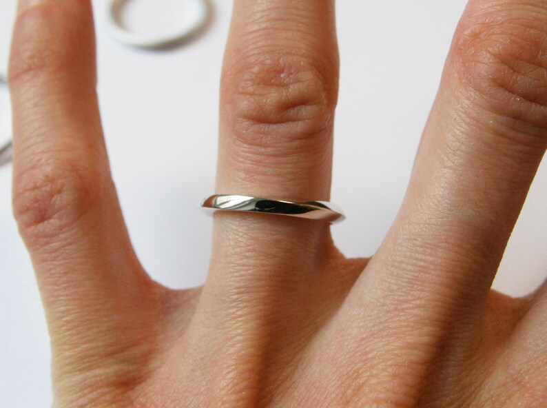 May include: A simple silver band ring worn on a finger.