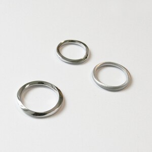 May include: Three silver rings, two with a smooth finish and one with a twisted design.