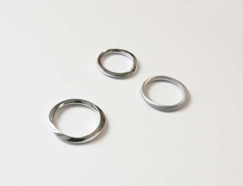 May include: Three silver rings, two with a smooth finish and one with a twisted design.