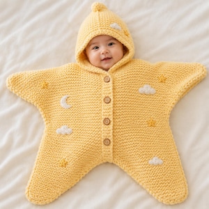 Könnte beinhalten: Ein gelber sternförmiger Baby-Overall mit Kapuze. Der Strick-Overall hat gestickte Wolken, Sterne und einen Mond. Er hat Holzknöpfe auf der Vorderseite. Das Baby trägt den Overall und lächelt.