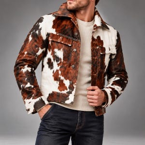 May include: A jacket featuring a brown and white cowhide print pattern, a classic collar, long sleeves with buttoned cuffs, and a front button closure with two chest pockets. The garment is worn over a plain cream-colored long-sleeve shirt.