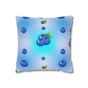 Può includere: Cuscino quadrato con sfondo azzurro e motivo di mirtilli e foglie verdi. I mirtilli sono di colore blu scuro e le foglie sono verdi. Il cuscino ha un aspetto morbido e strutturato.