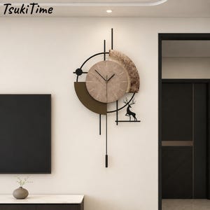 May include: A wall clock featuring a circular beige face with thin black hands and markers. The clock is mounted on a black metal frame with a dark brown semi-circle, a textured wood-grain arc, and a black silhouette of a deer standing on a shelf.