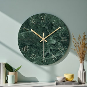 Könnte beinhalten: Eine runde Wanduhr mit einem dunkelgrünen Marmormuster auf dem Zifferblatt, goldenen römischen Ziffern und dünnen goldenen Zeigern. Die Uhr zeigt den kleinen Text "time the time that belongs to you" in Gold auf der linken Seite des Zifferblatts.