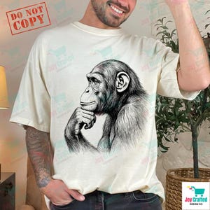 May include: Cream-colored t-shirt featuring a detailed black and white illustration of a chimpanzee in a thoughtful pose. The shirt has a relaxed fit. The words "DO NOT COPY" are printed in a red box in the upper left corner.