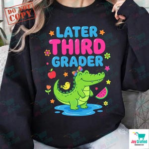 Könnte beinhalten: Schwarzes Sweatshirt mit dem Text "LATER THIRD GRADER" in Blau und Pink. Auf der Vorderseite sind ein Cartoon-Alligator mit Schleife, ein gelber Vogel, eine Wassermelonenscheibe und andere Grafiken abgebildet.
