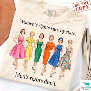 Könnte beinhalten: Ein cremefarbenes T-Shirt mit einer Grafik von sechs Figuren in Vintage-Kleidern und dem Text Women's rights vary by state. Men's rights don't. Die Figuren tragen Kleider in Pink, Gelb, Grün, Orange, Blau und mit Blumenmuster.