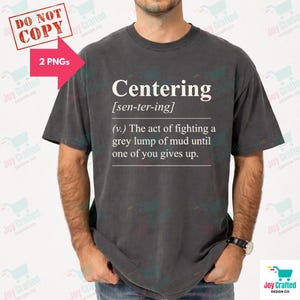 May include: Dark grey t-shirt with the word "Centering" in white, along with a definition. The definition reads: "(v.) The act of fighting a grey lump of mud until one of you gives up."