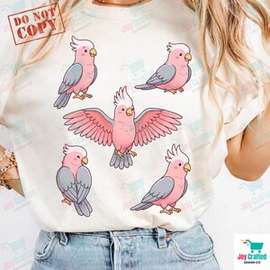 May include: White t-shirt featuring a pattern of pink and gray cockatoo illustrations. The birds are depicted in various poses, including one with outstretched wings. The text "DO NOT COPY" is in the upper left corner.