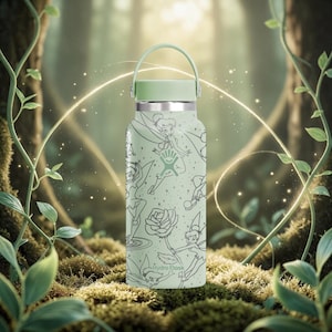 Puede incluir: Una botella de agua Hydro Flask verde claro con asa y tapa a juego. La botella presenta un patrón de ilustraciones de Campanilla y otros temas de hadas. El logotipo de Hydro Flask es visible. El fondo es una escena de bosque.