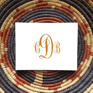 May include: A white card with a monogram of the letters "CDB" in a cursive font. The letters are in a burnt orange color.